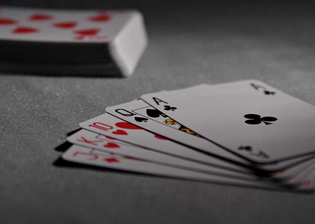 A hand of cards laid out on a table with a deck of cards in the background.