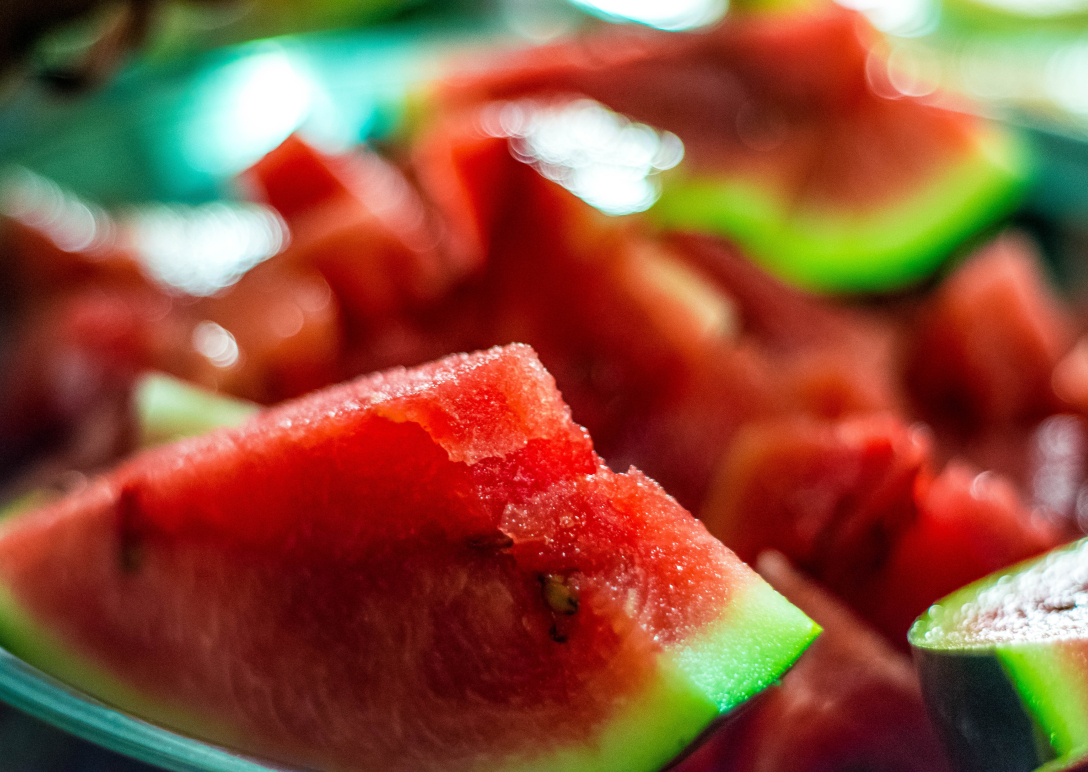 a plate of cut-up watermelon with one triangular slice in the foreground.