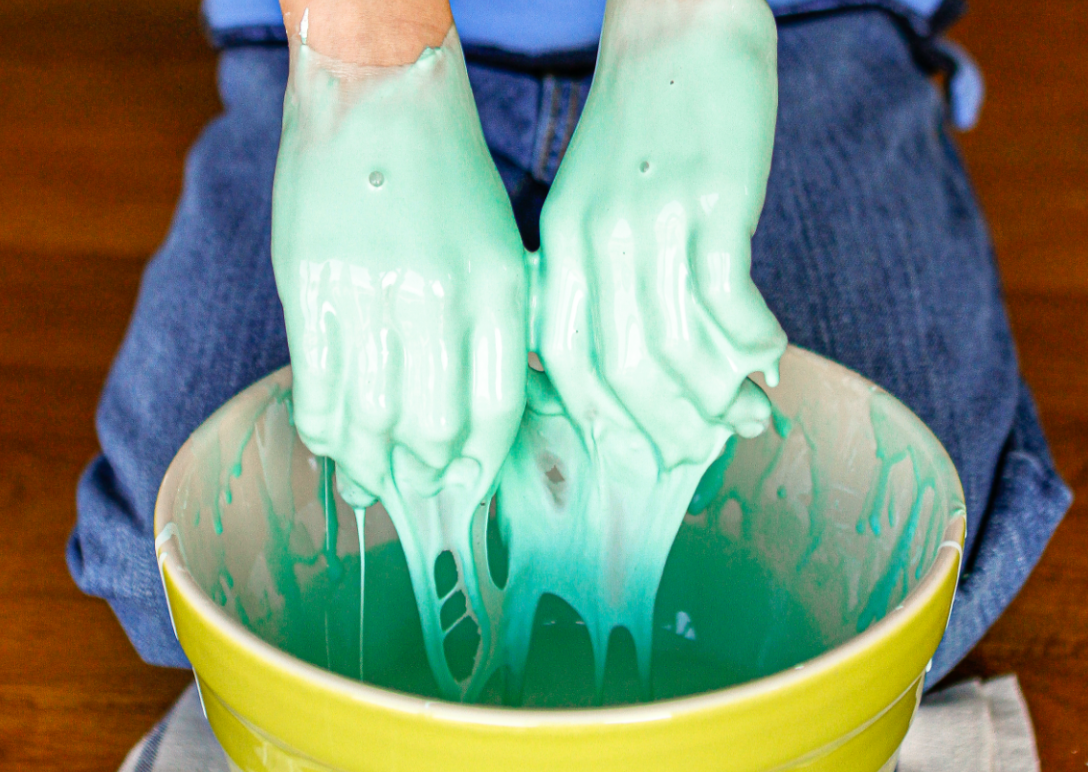 Two hands covered in non-Newtonian fluid. The fluid is dyed light green.