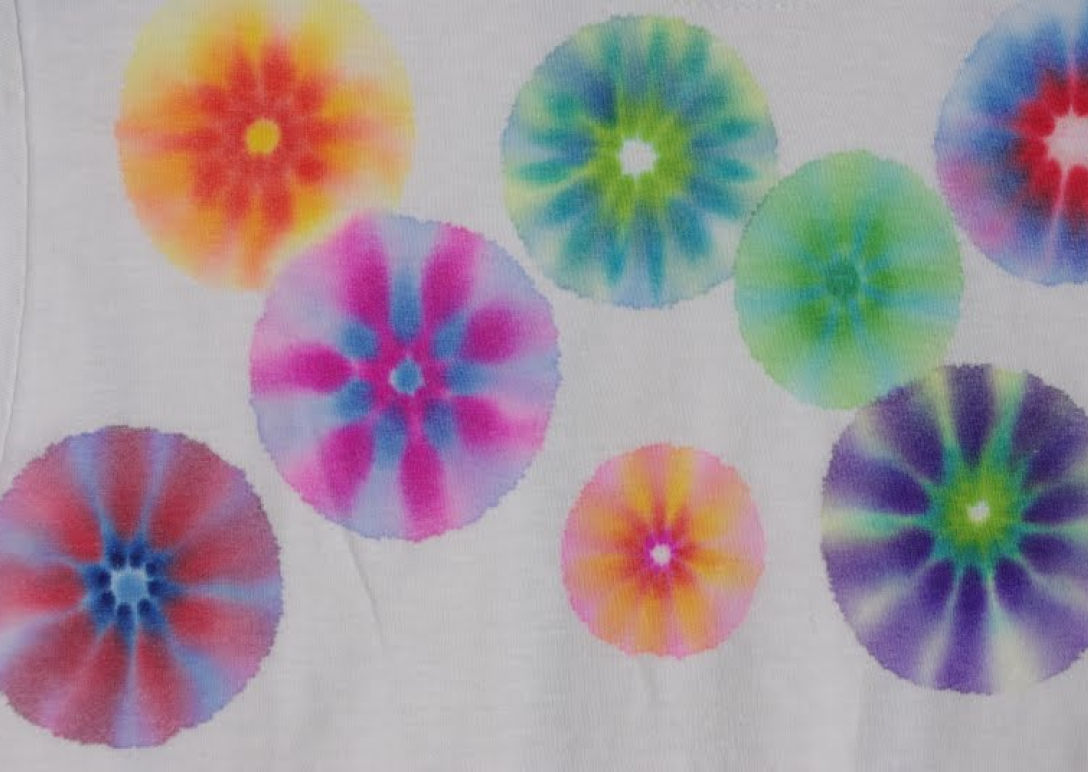a white t-shirt with several patches of colorful tie-dye across the front.