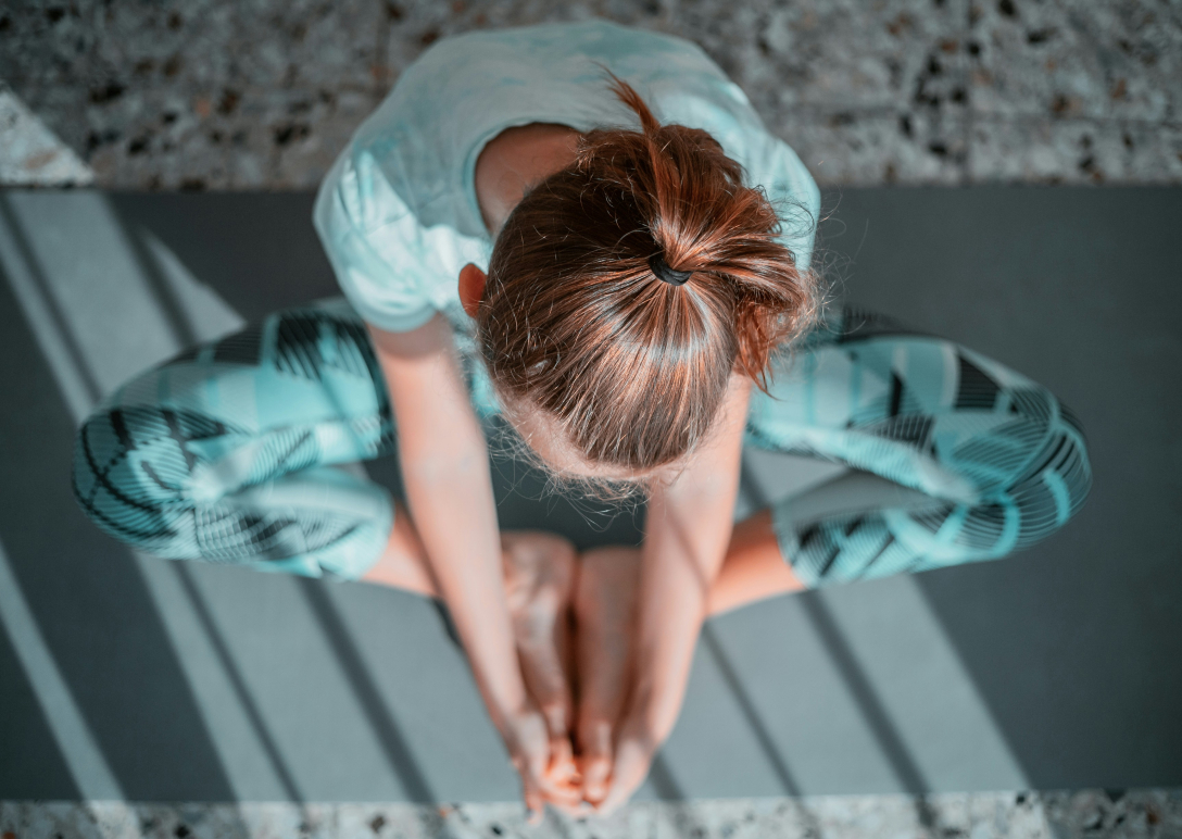 A teen girl practices yoga on a yoga mat