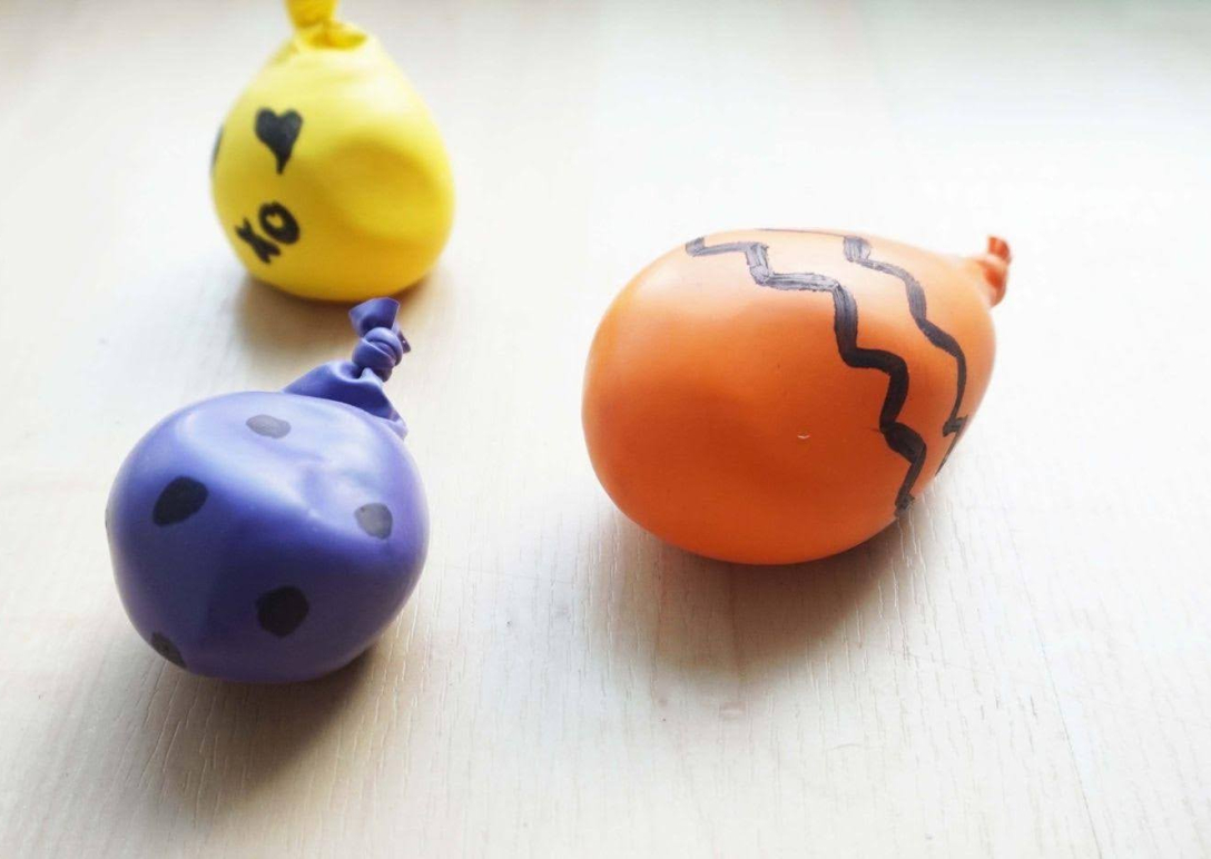 Three decorated, homemade stress balls made from balloons and cornstarch sitting on a table
