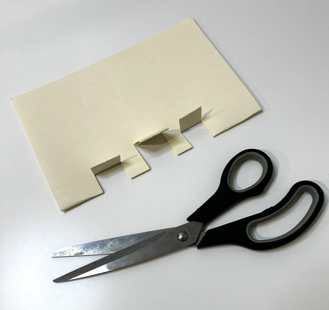 Cut out tabs on piece of paper with scissors. 