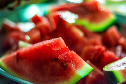 a plate of cut-up watermelon with one triangular slice in the foreground.