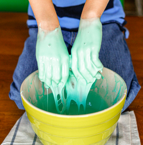Two hands covered in non-Newtonian fluid. The fluid is dyed light green.