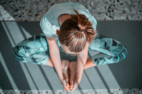 A teen girl practices yoga on a yoga mat