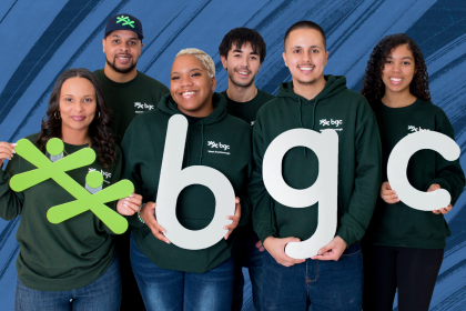 A group of smiling Club staff holding the green jacks and letters B G C